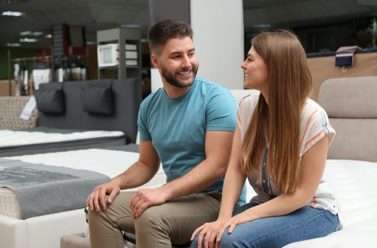 Két ember ül egy matracon egy bemutatóteremben